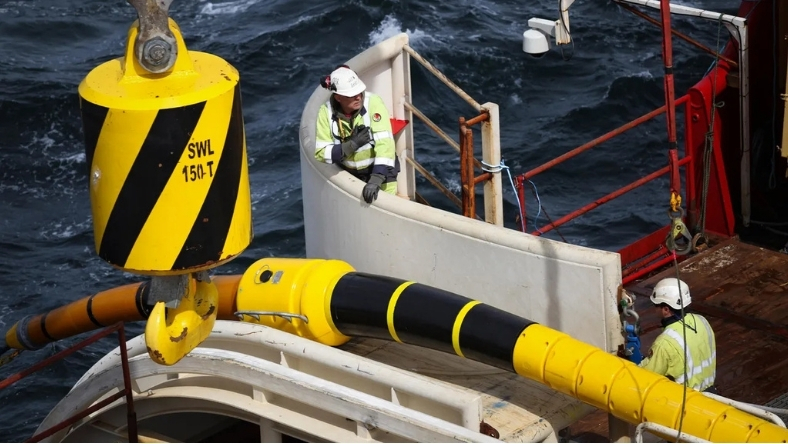 Technicians handling subsea power cable during offshore installation